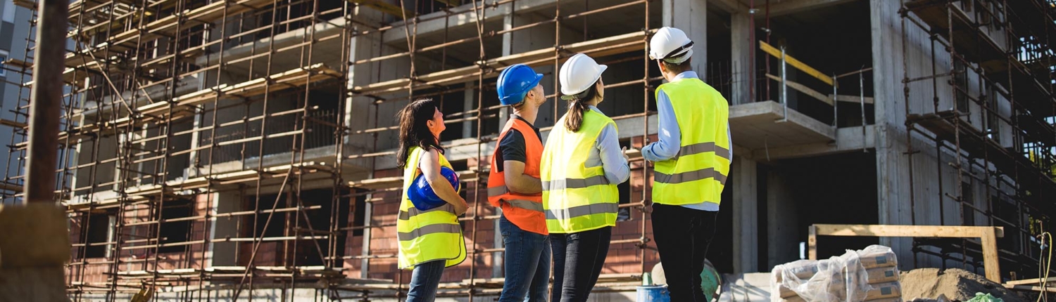 Back view of four construction workers standing next to each other at a construction site